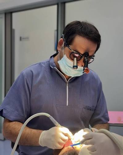 Dr. İkram Sadıqov binokulyar lupa ilə pasiyentə müalicə aparır